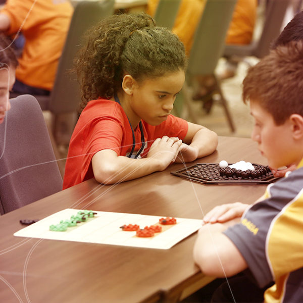 crianças concentradas usando o tabuleiro octi com jogos de raciocínio para crianças